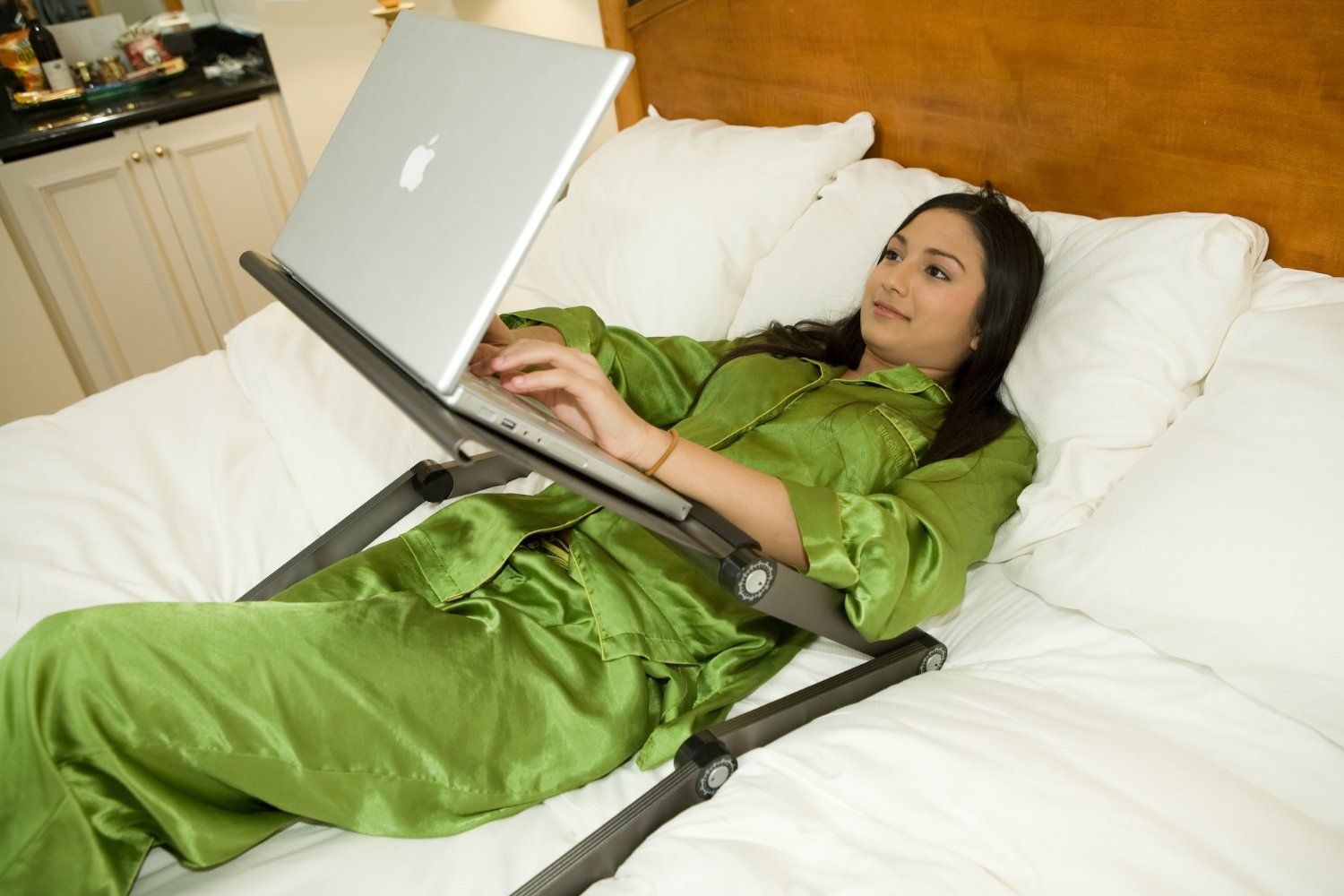 Girl Lying in bed with laptop on stand.